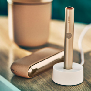 A bright IQOS ILUMA Pocket Charger and Holder in a person's hand. 